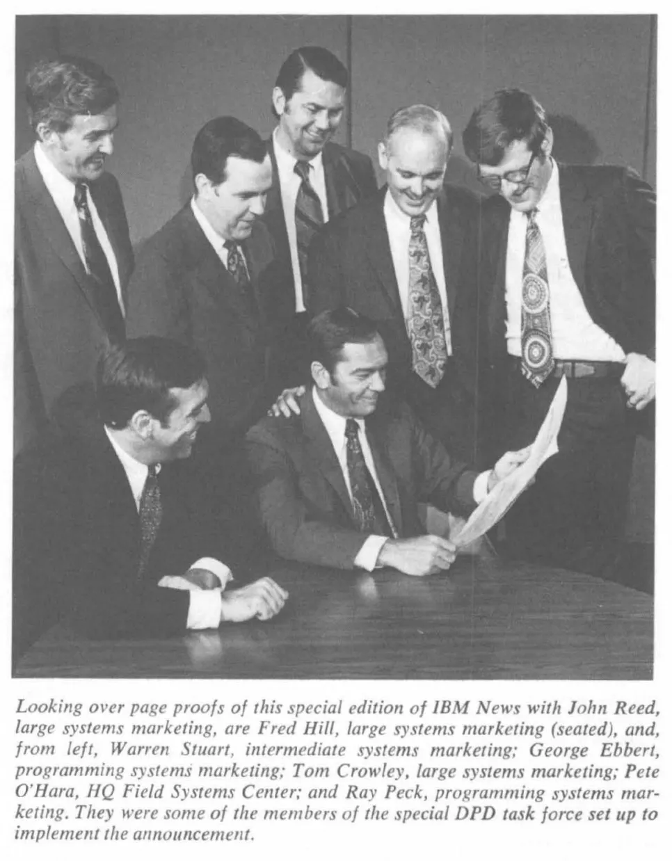 IBM staff in dark suits and ties reviewing page proofs of IBM News, 1972